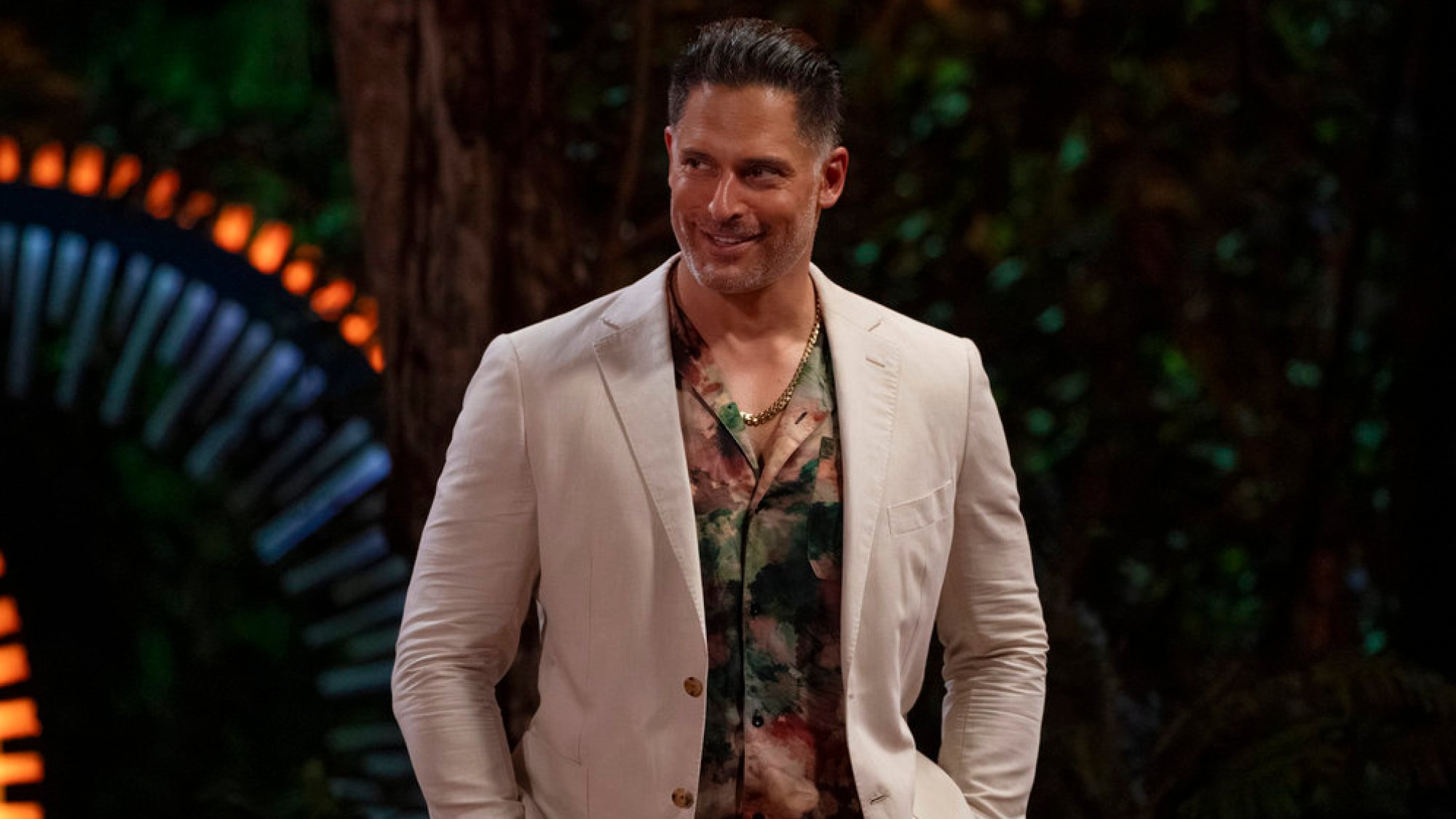 Joe Manganiello wears a tan suit and a smile during an episode of Deal or No Deal Island.